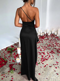 Woman in a black dress standing in a room with candles and rose petals on the floor.