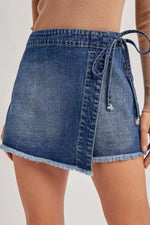 Denim skirt with a tie waist on a plain background