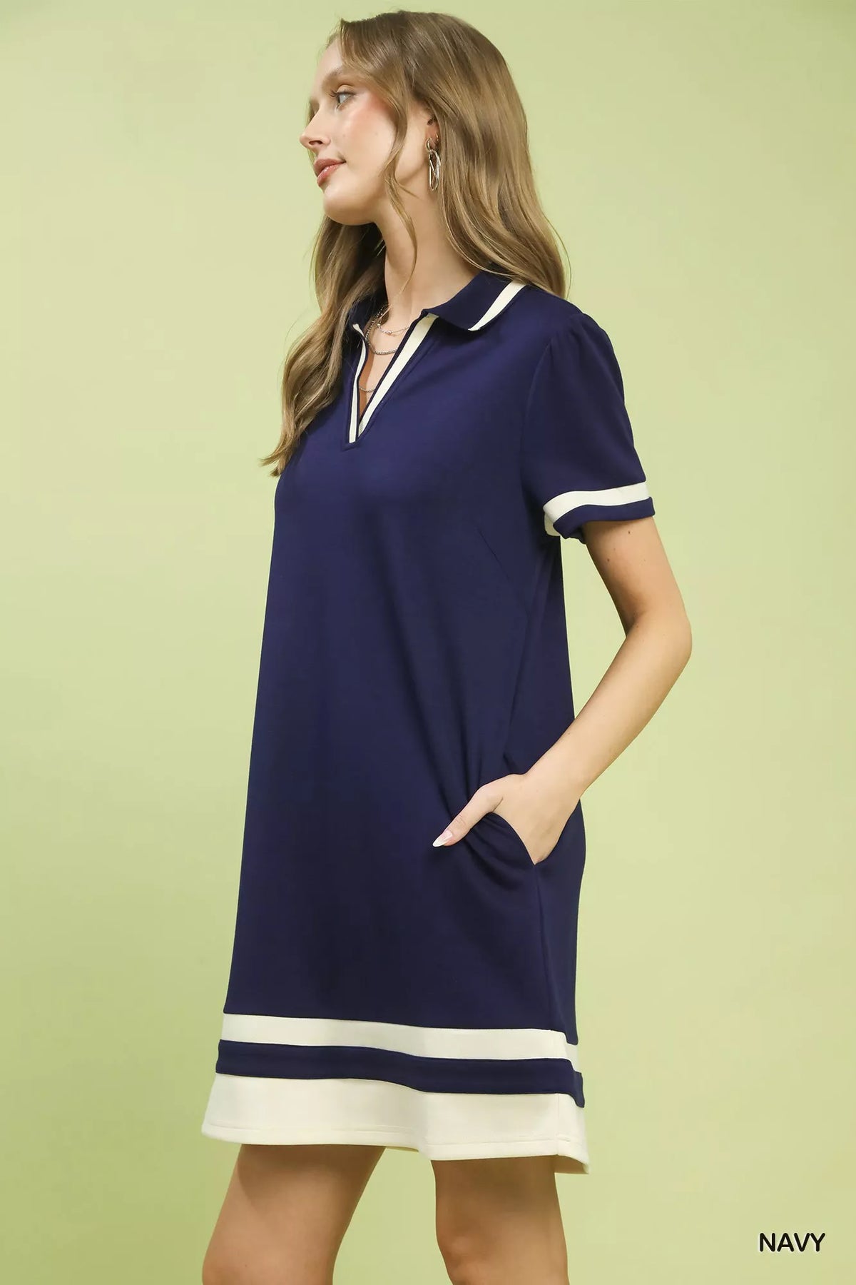 Woman wearing a navy dress with white accents on a light green background