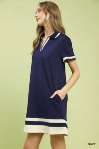 Woman wearing a navy dress with white accents on a light green background