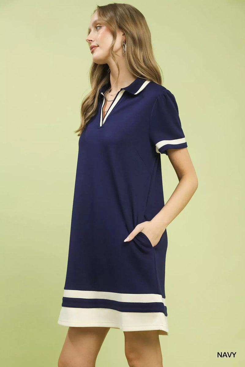 Woman wearing a navy dress with white accents on a light green background