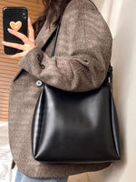 Person holding a black handbag with a neutral background
