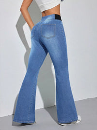 Person wearing blue flared jeans on a plain background