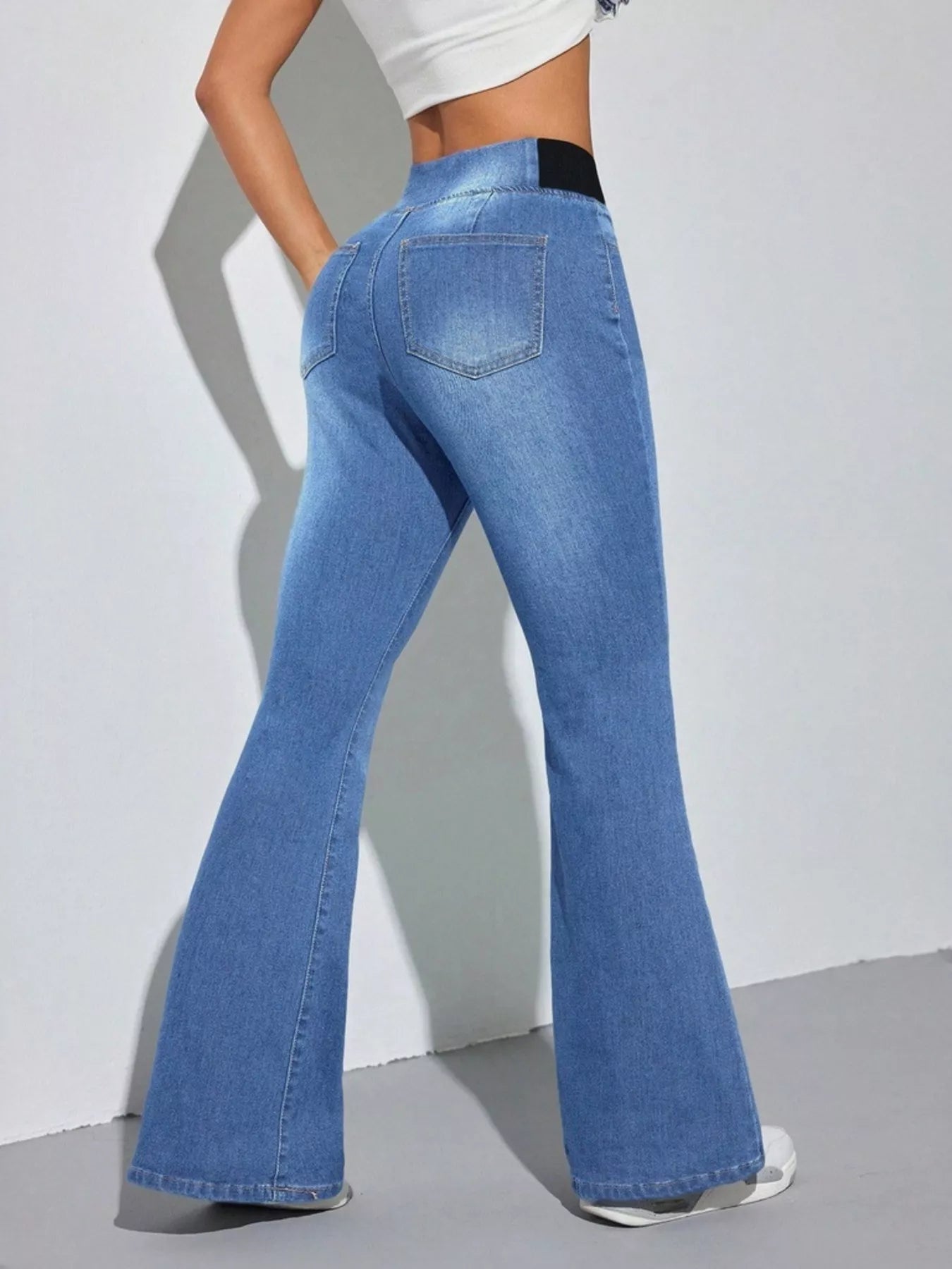 Person wearing blue flared jeans on a plain background