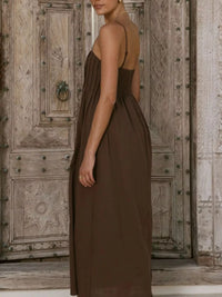 Woman wearing a brown dress standing in front of an ornate wooden door.