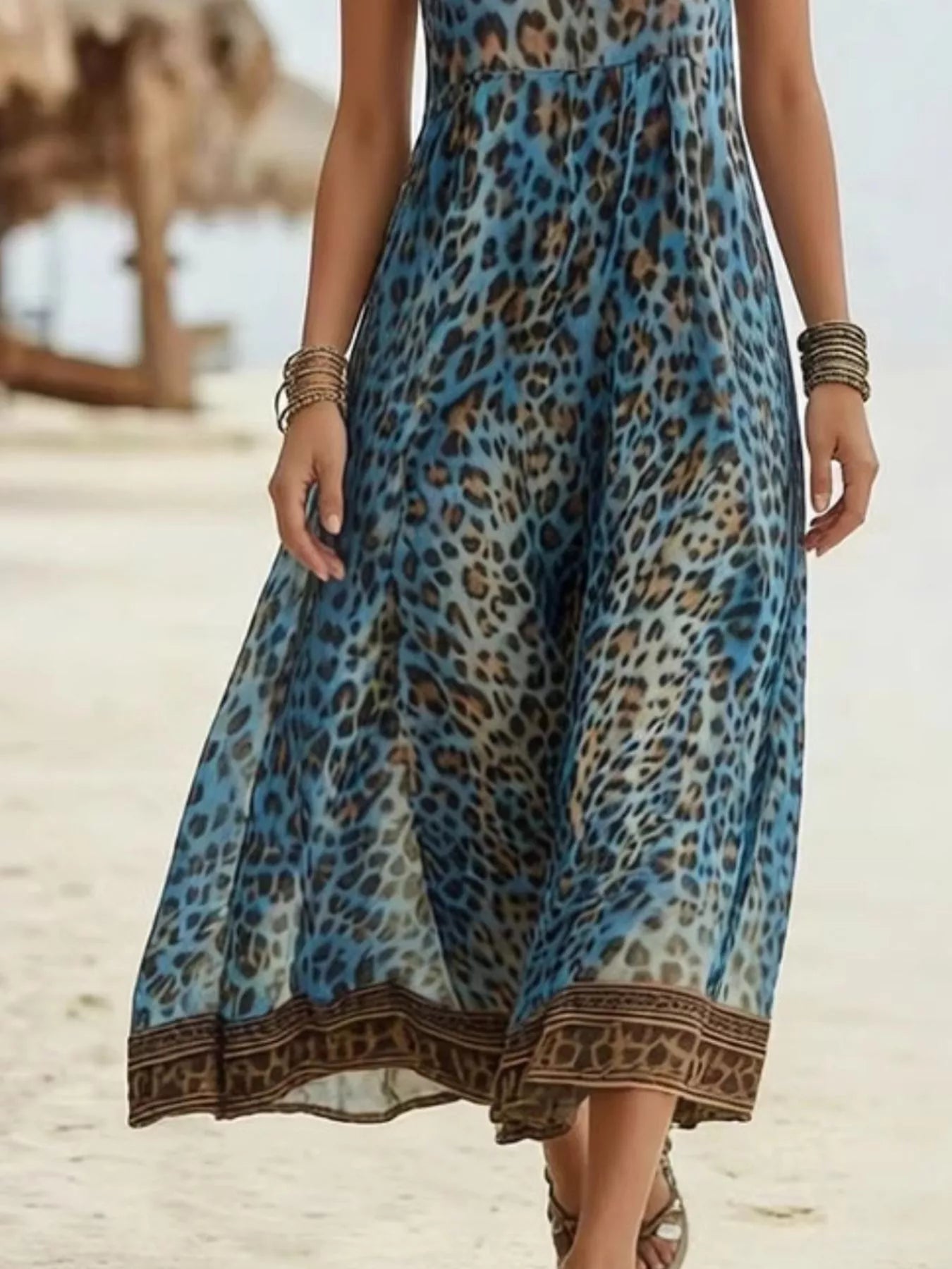Woman wearing a blue leopard print dress on a beach.
