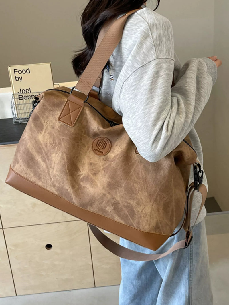 Person holding a large brown leather handbag indoors