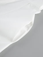 Close-up of a white satin pillowcase on a gray background