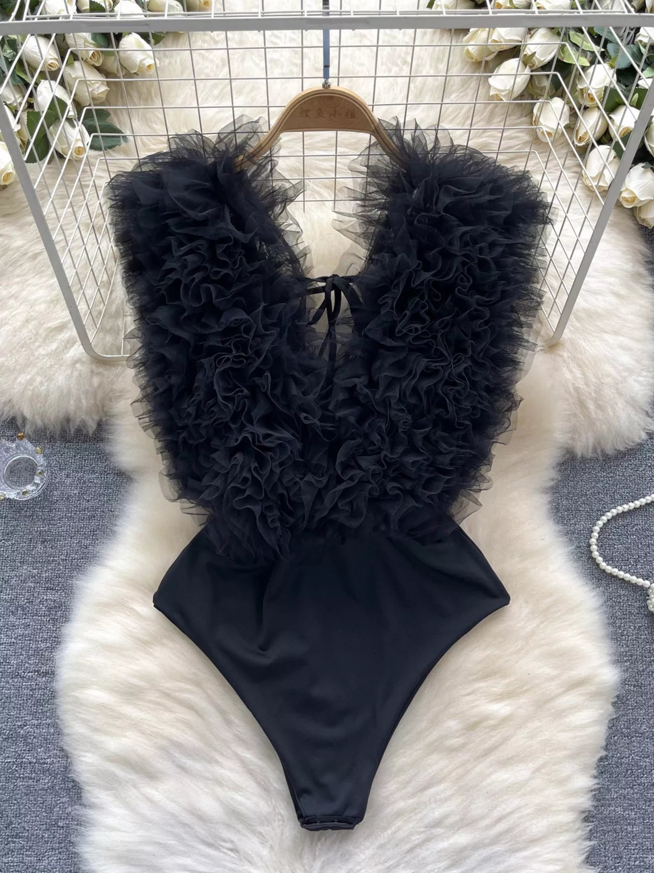 Black ruffled swimsuit on a fluffy white rug