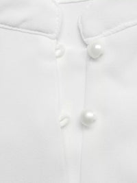 Close-up of a white buttoned shirt with pearl-like buttons on a light gray background