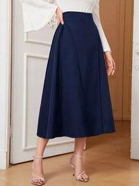 Person wearing a navy blue skirt with a white top in an indoor setting.