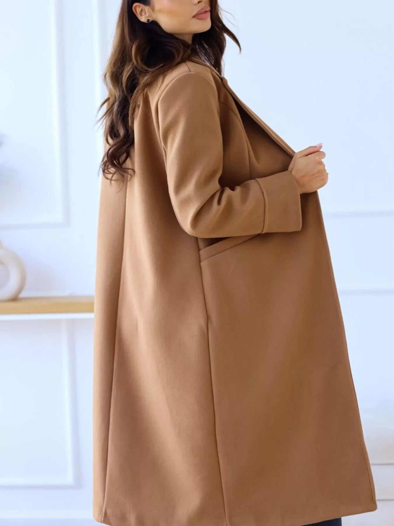 Woman wearing a brown coat against a white background