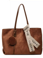 Brown leather tote bag with a decorative strap on a white background
