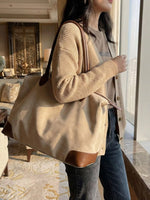 Person holding a beige tote bag in an indoor setting