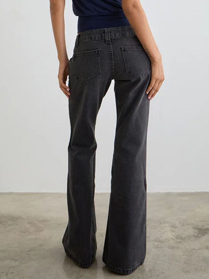 Person wearing dark gray flared jeans against a plain background