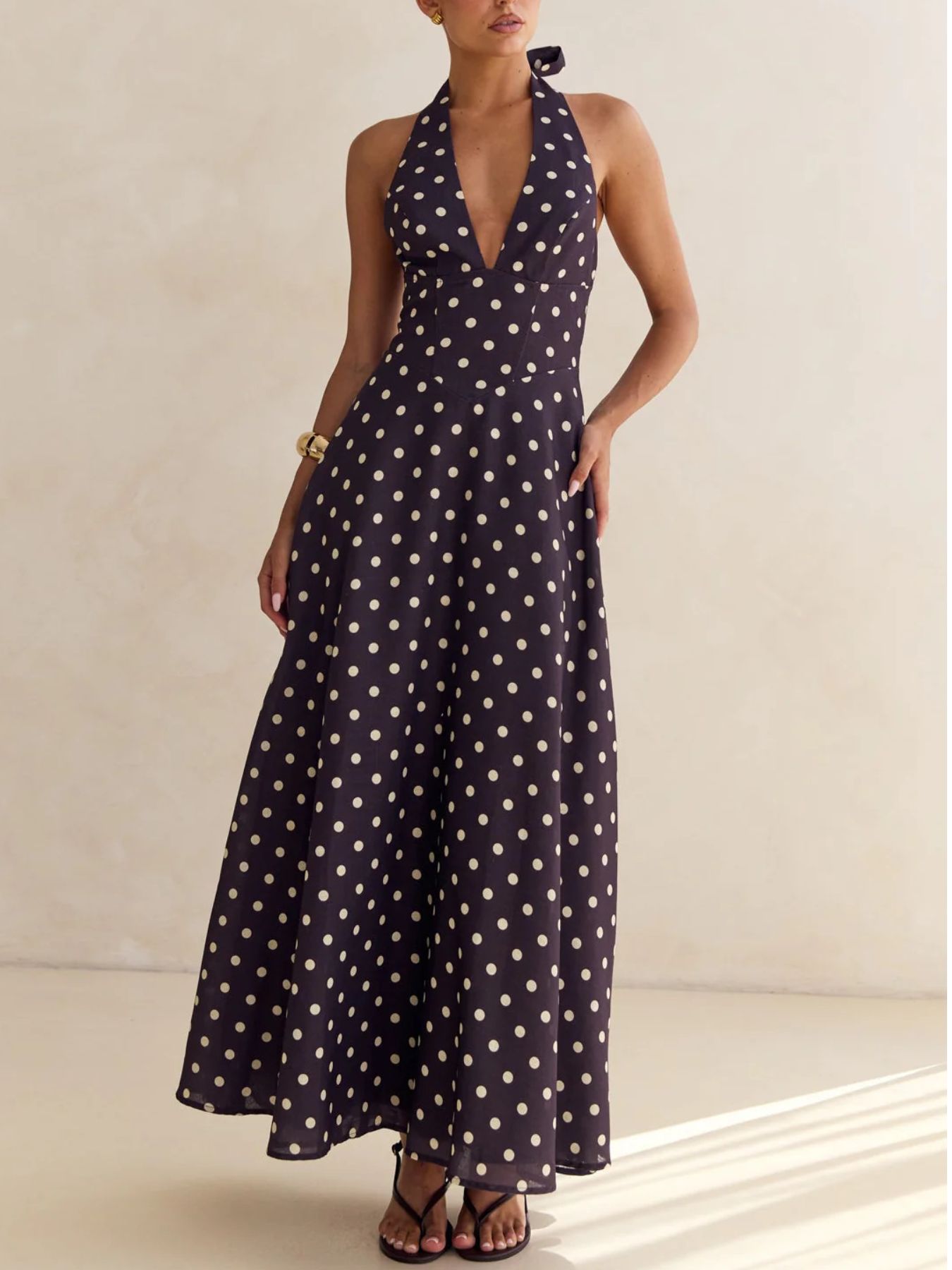 Woman wearing a navy blue dress with white polka dots against a neutral background