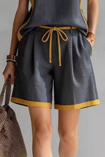 Person wearing gray shorts with yellow trim on a plain background