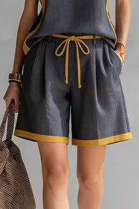 Person wearing gray shorts with yellow trim on a plain background