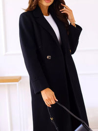 Woman wearing a long black coat with a white background