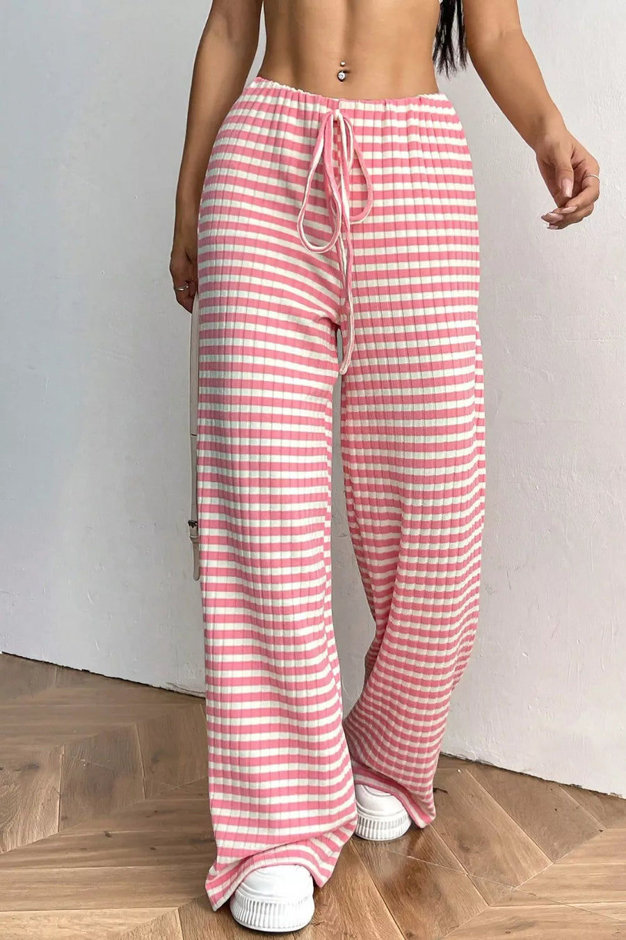Person wearing pink and white striped pants on a wooden floor.