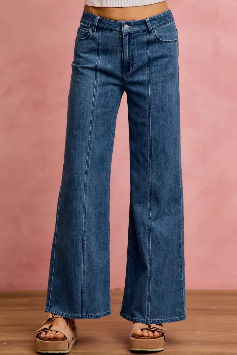 Wide-leg jeans worn by a person on a pink background