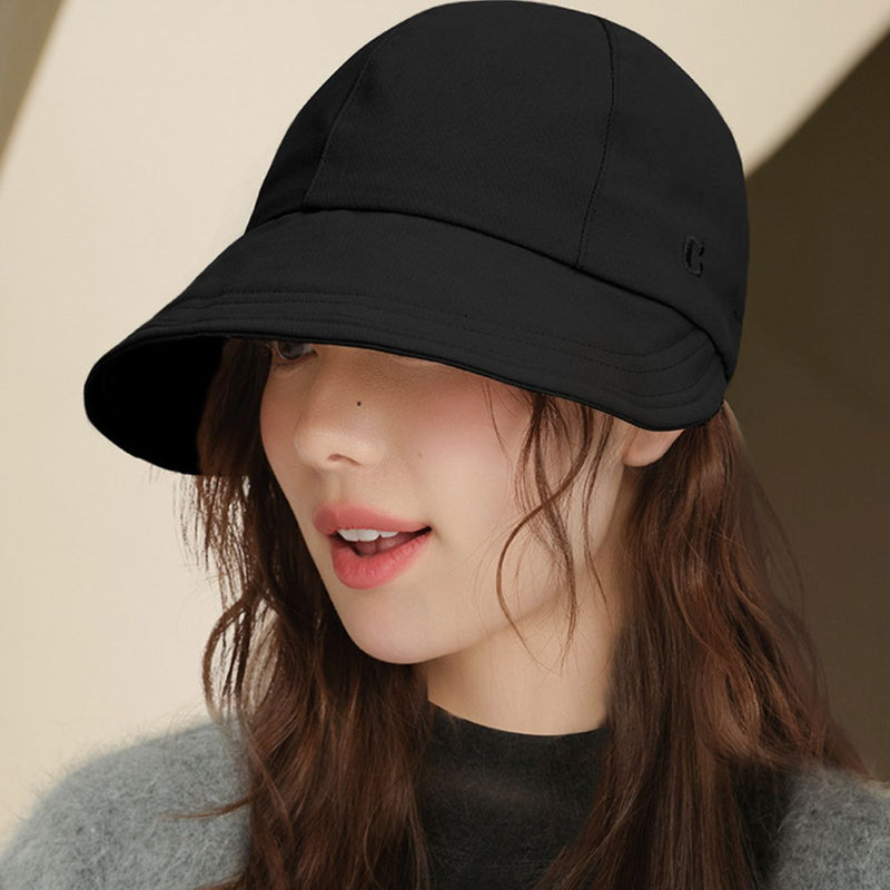Woman wearing a black cap against a neutral background