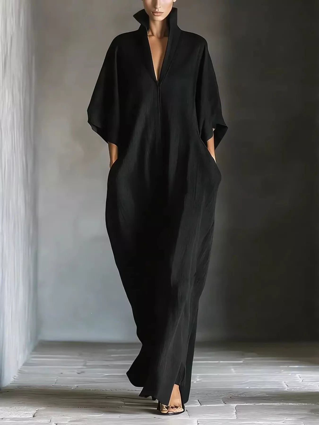 Person wearing a black outfit standing in a minimalistic setting