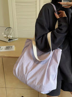 Person holding a light purple tote bag in an indoor setting