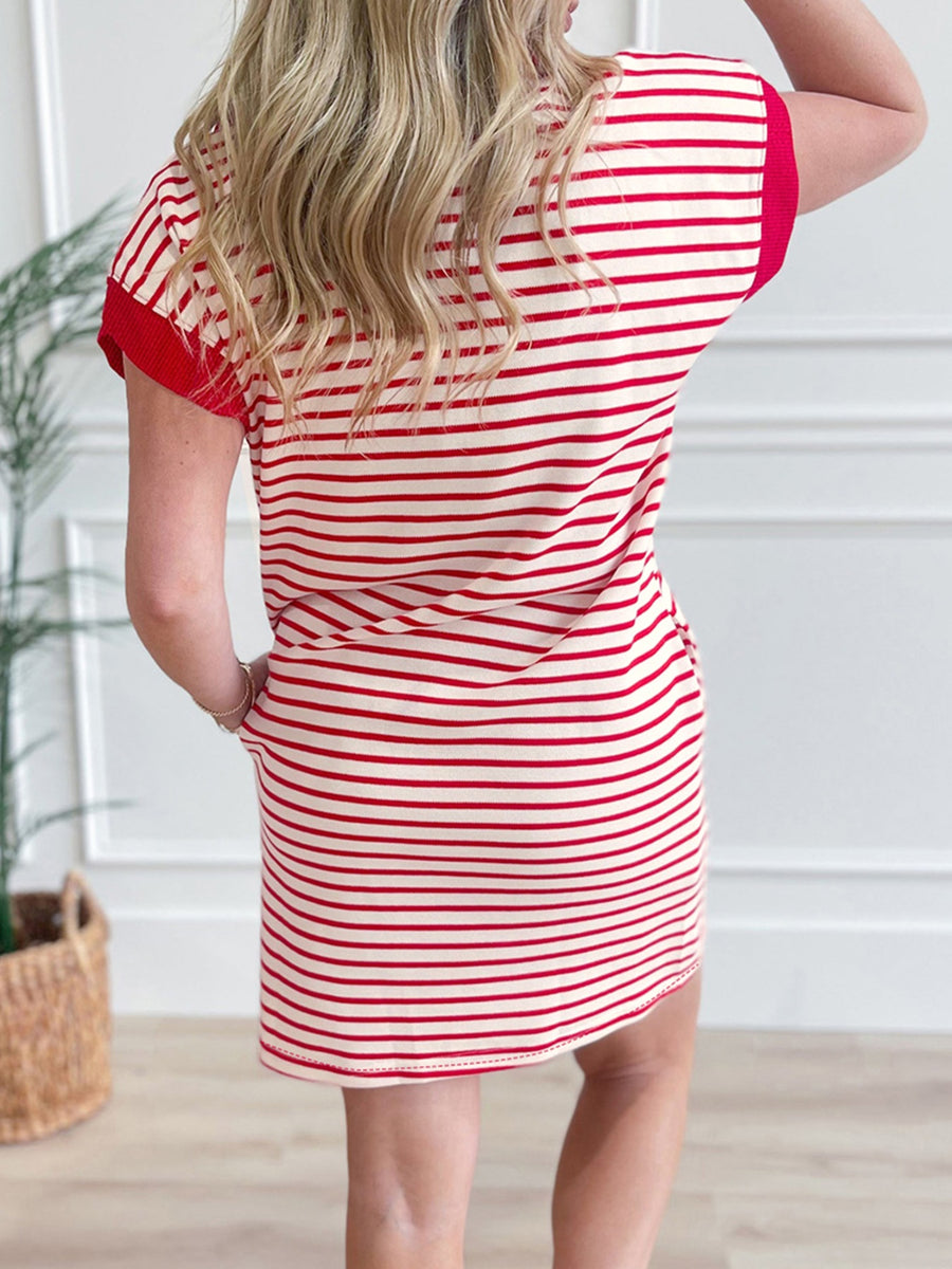 Woman wearing a red and white striped dress in a minimal indoor setting.