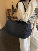 Person holding a black duffel bag indoors