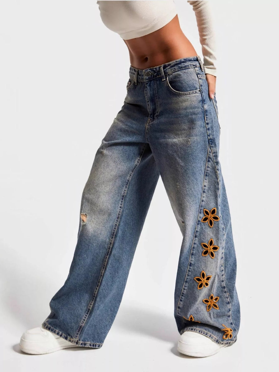 Wide-leg jeans with floral embellishments on a white background