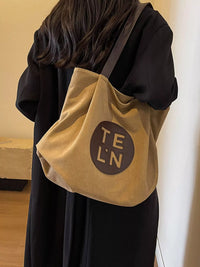 Person wearing a beige tote bag with 'TE LN' logo