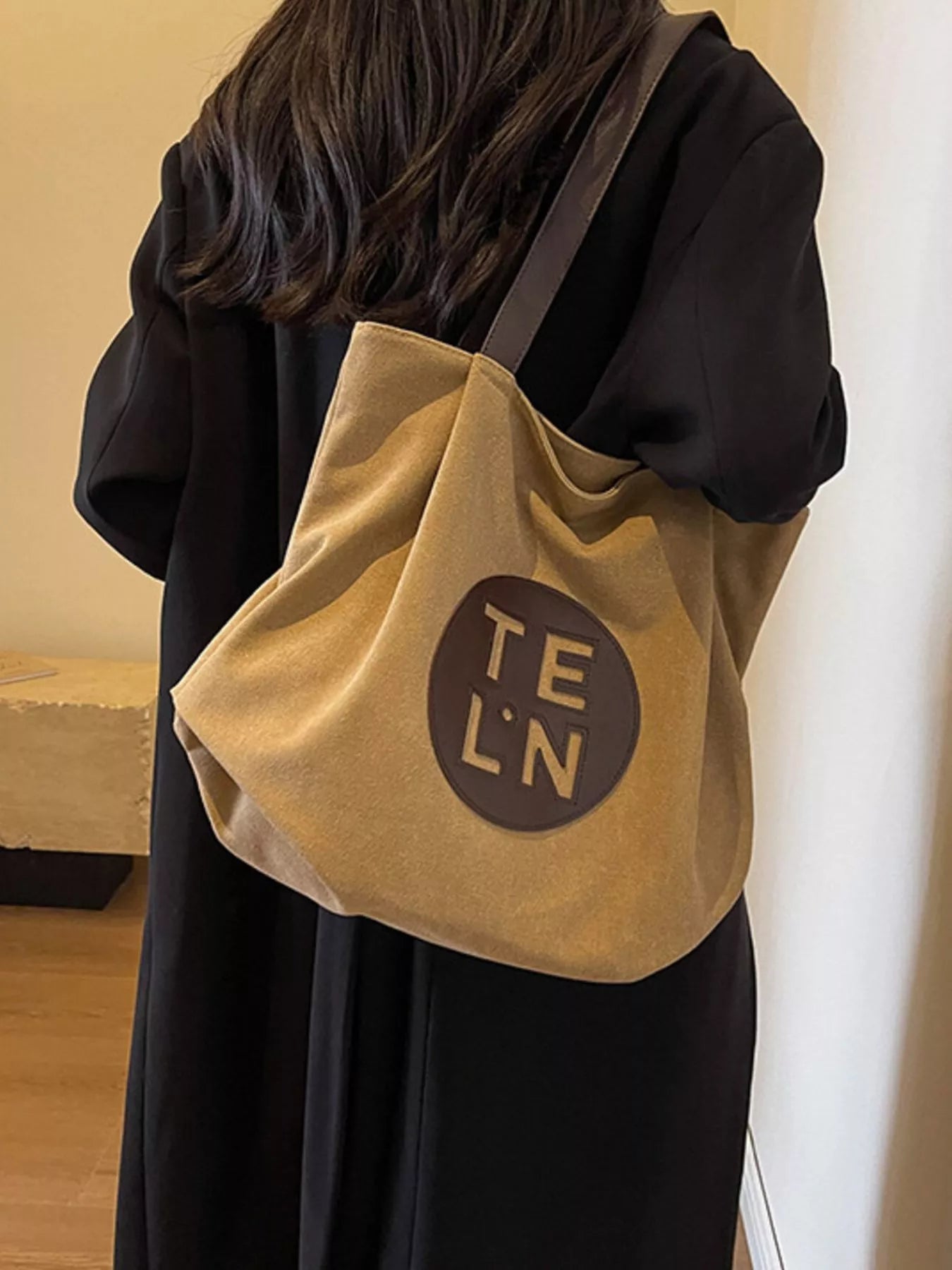 Person wearing a beige tote bag with 'TE LN' logo