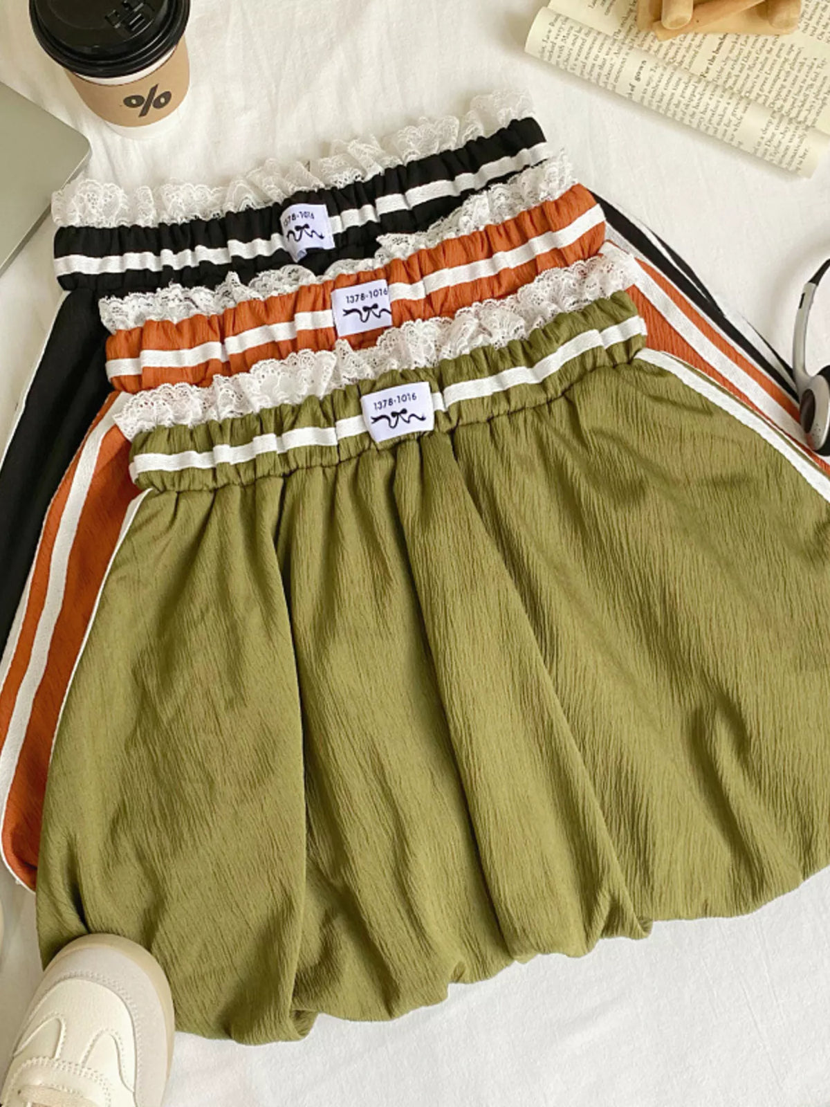 Stack of colorful shorts with lace trim on a white surface