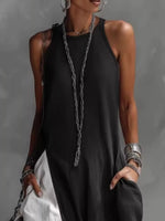 Person wearing a black sleeveless top with a long necklace against a gray background