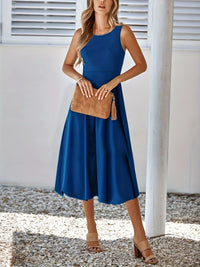 Woman wearing a blue dress holding a brown clutch against a white background