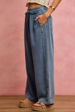 Person wearing wide-leg jeans against a pink background