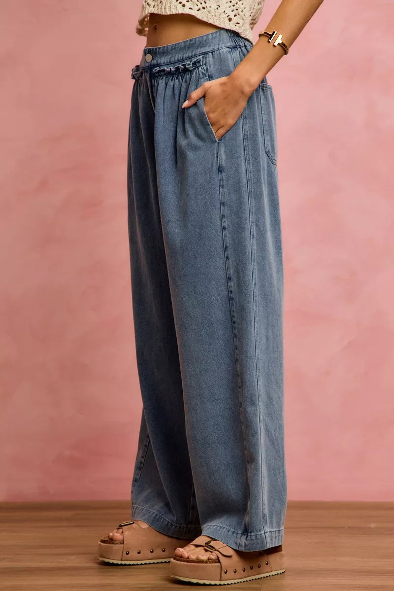 Person wearing wide-leg jeans against a pink background
