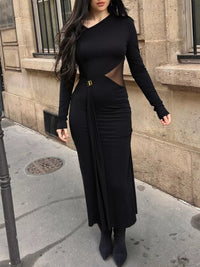 Woman wearing a black long-sleeve dress with cut-out details on a city street.