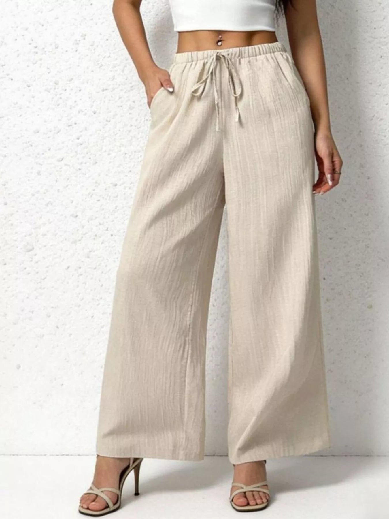 Beige wide-leg pants worn by a person on a white background