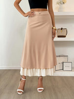 Person wearing a beige skirt with a white bottom layer, standing indoors.
