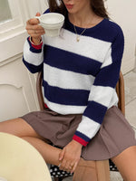 Person wearing a blue and white striped sweater holding a cup.