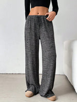 Person wearing dark gray checkered pants and a black top on a white background