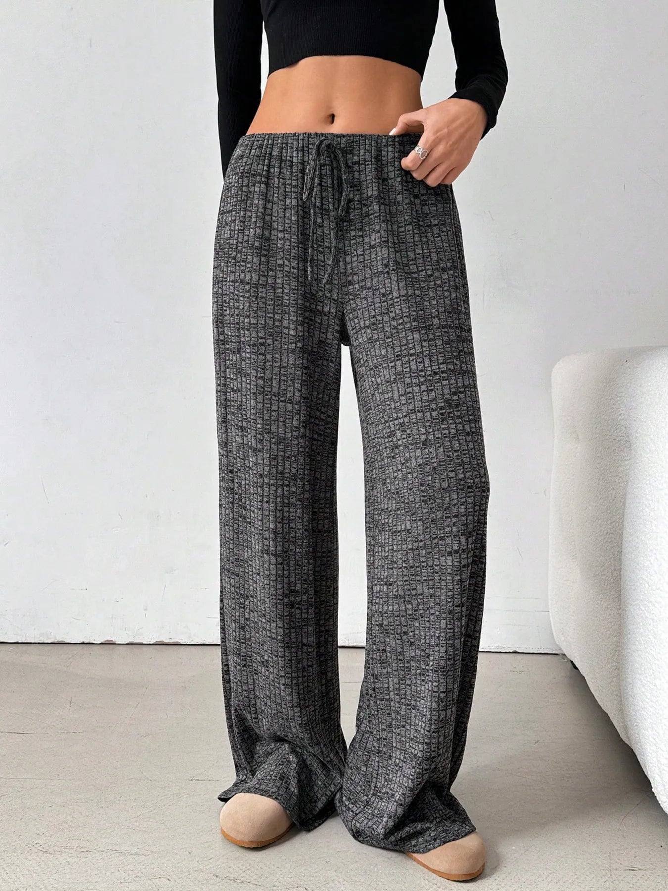 Person wearing dark gray checkered pants and a black top on a white background