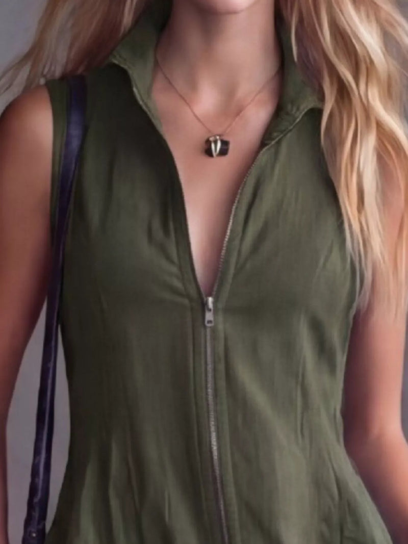 Person wearing a green sleeveless top with a zipper, standing against a neutral background.