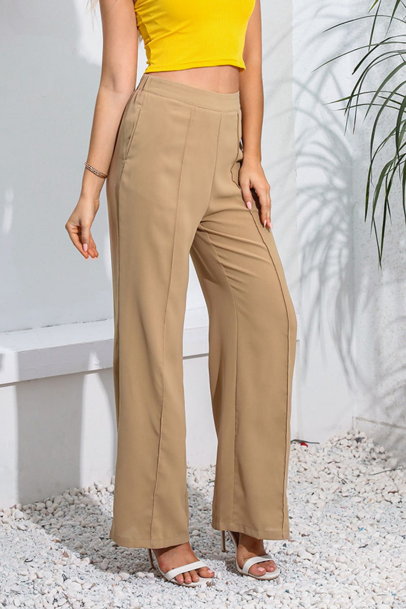 Person wearing beige wide-leg pants and a yellow top outdoors.