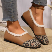 Brown loafers with leopard print soles and white fur trim worn with jeans.