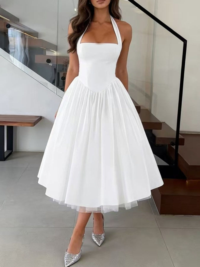 Woman wearing a white halter neck dress in an indoor setting