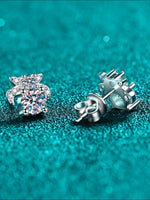 Silver earrings with a clear gemstone on a teal glittery background
