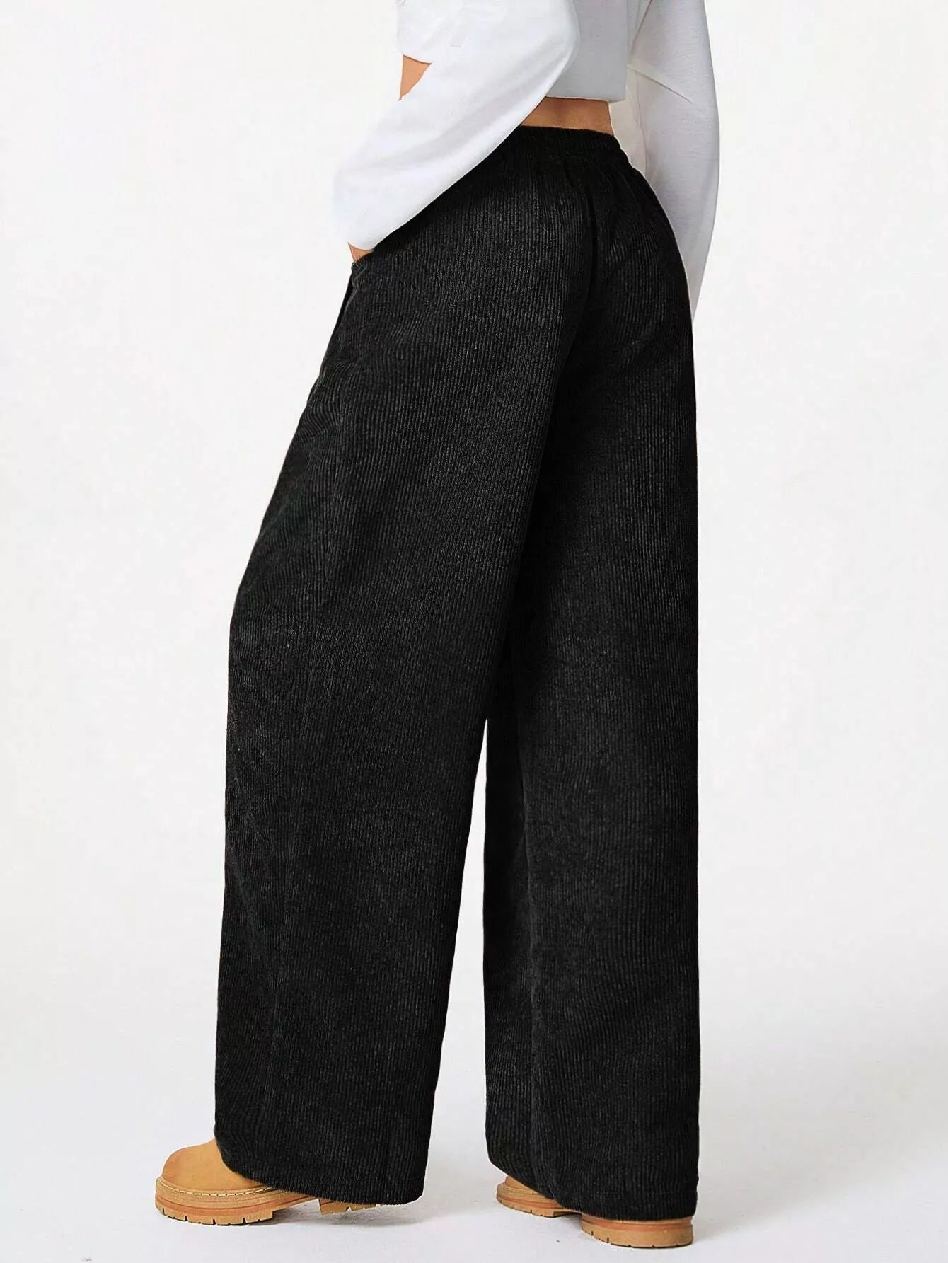 Person wearing black wide-leg pants on a white background